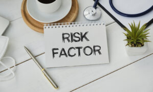 Risk Factor handwritten on paper note with stethoscope on wooden table