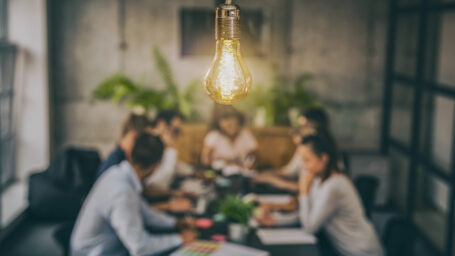 Young business people are discussing together a new startup project. A glowing light bulb as a new idea.